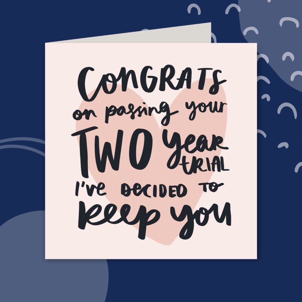 Image shows a greeting card against a navy background. The card is pale pink with a slightly darker pink heart drawn in the middle. Over the heart, it reads 